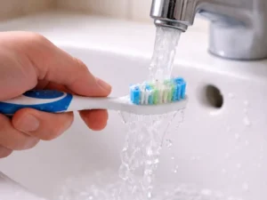 Rinsing the toothbrush under clear water